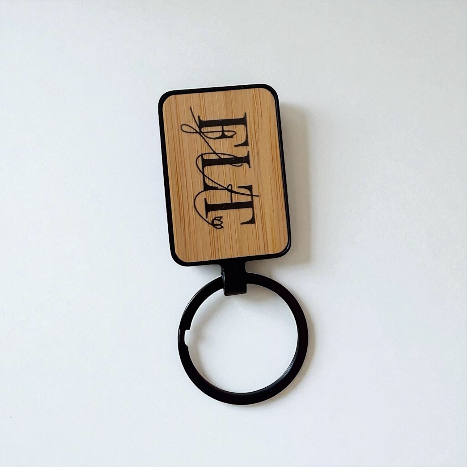Porte-clés en bois de bambou et métal noir avec le logo FLT imprimé.