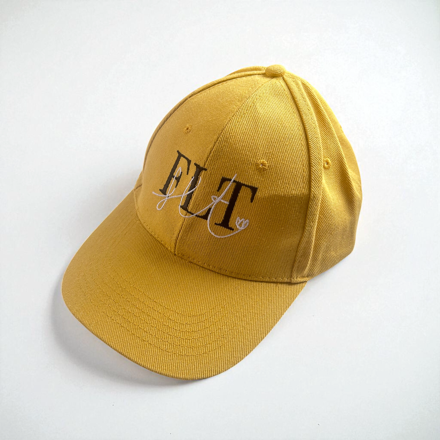 Casquette FLT jaune avec broderie du logo FLT en noir et blanc, vue de profil.