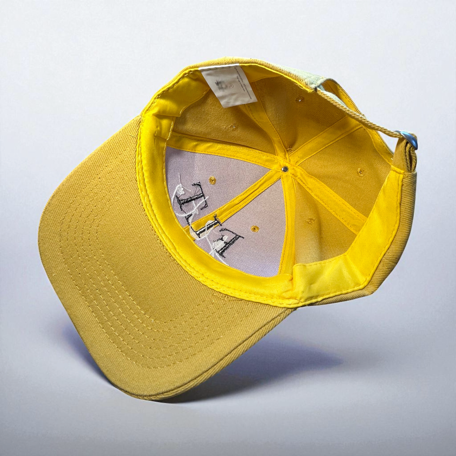 Vue de l'intérieur de la casquette FLT jaune, montrant les coutures et l'étiquette.
