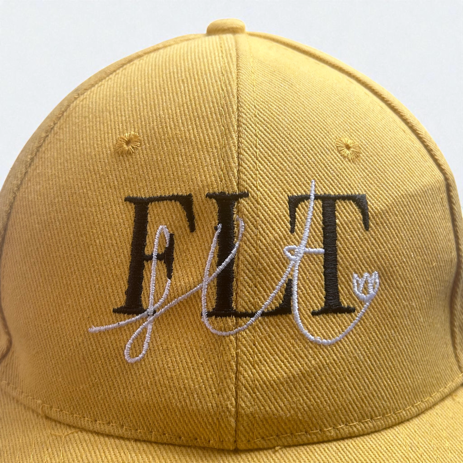 Casquette FLT jaune en coton recyclé avec le logo brodé en noir et blanc.